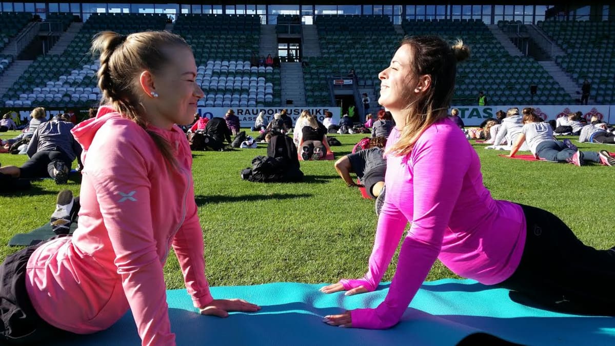 Kaksi naista venyttelee Kupittaan jalkapallostadionilla.