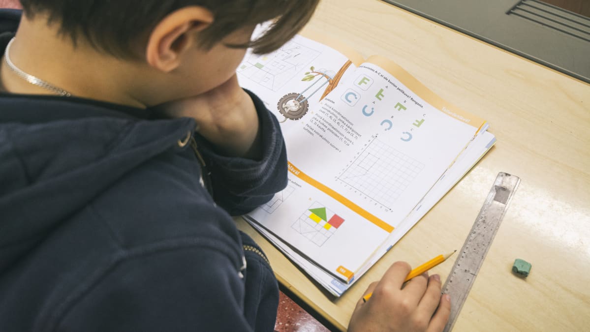 Poika tekee matematiikan tehtäviä.