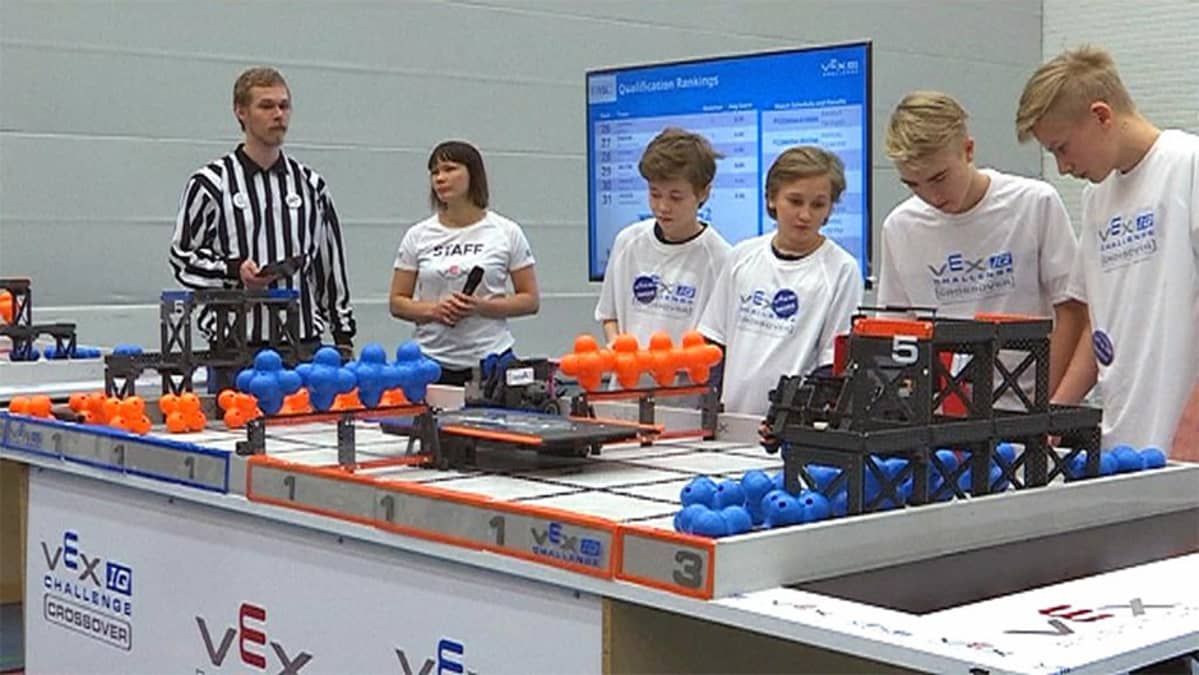 Robotiikan SM-kisatilanne, tuomari seuraa neljän pojan joukkueen toimintaa