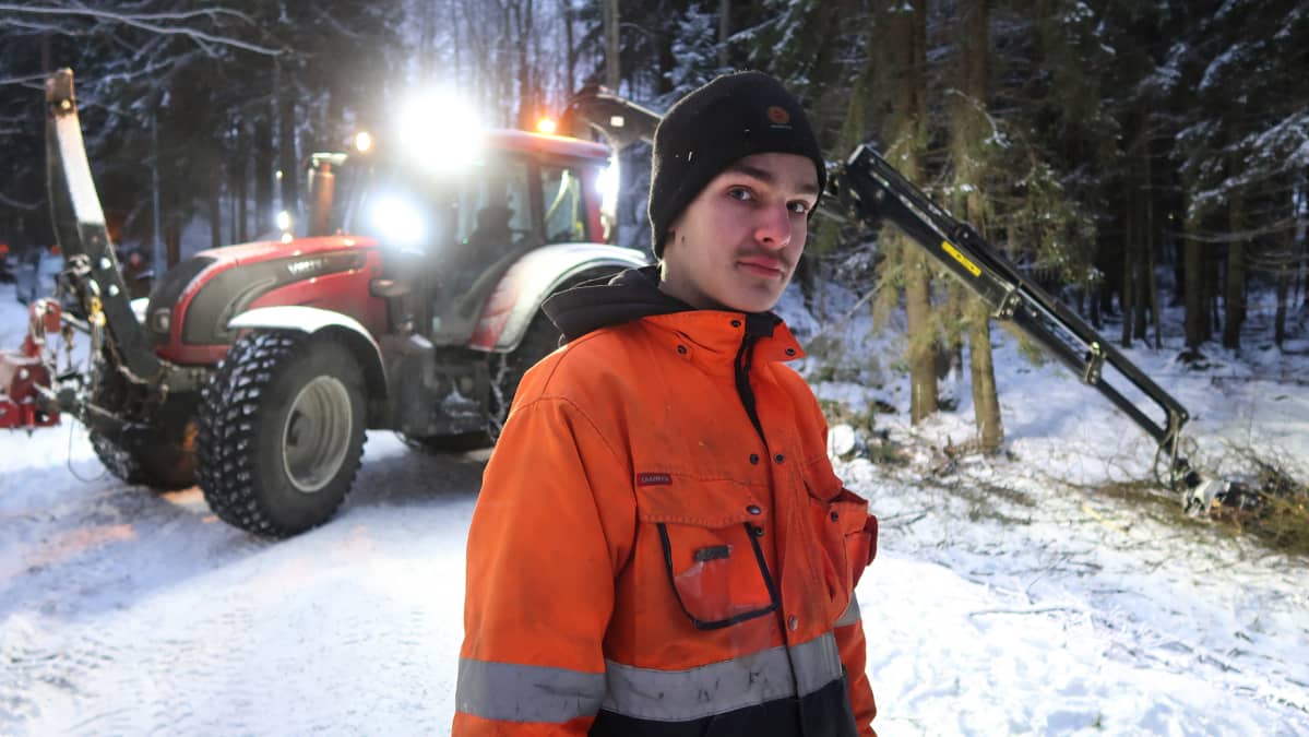 eemeli hursti seisoo metsätiellä, taustalla metsätraktori.