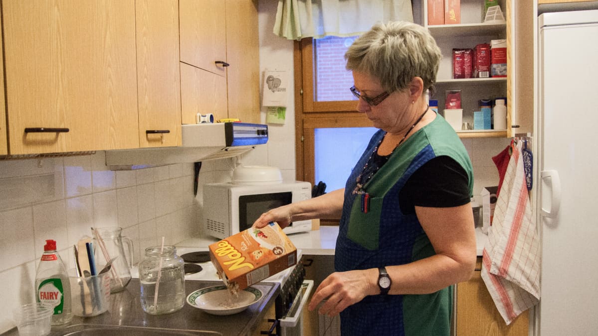 Hyrynsalmelainen kotihoitaja Paula Keränen tekee puuroa vanhuksen keittiössä.
