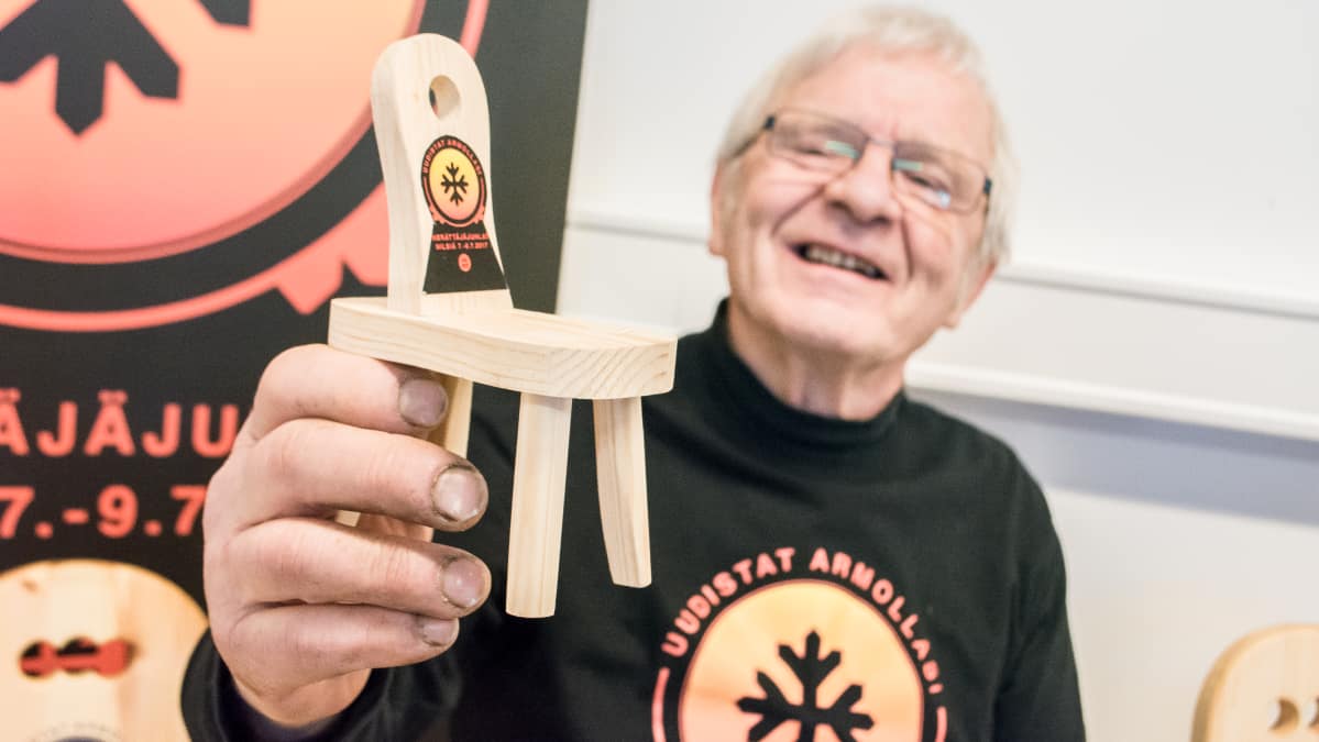 Erkki Rissanen pitää kädessään minikokoista Paavon palli -puutuolia.