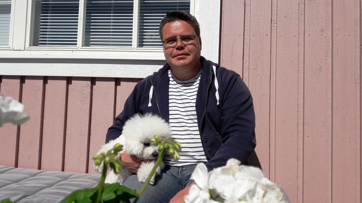 Jukka Ylimäki Alma-koira sylissään.
