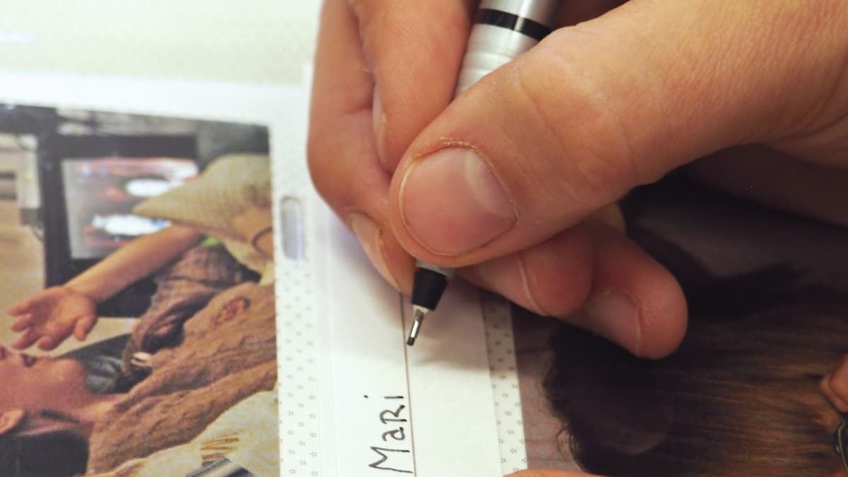 Valokuva-albumiin kirjoitetaan kuvateksti arkistointitussilla.