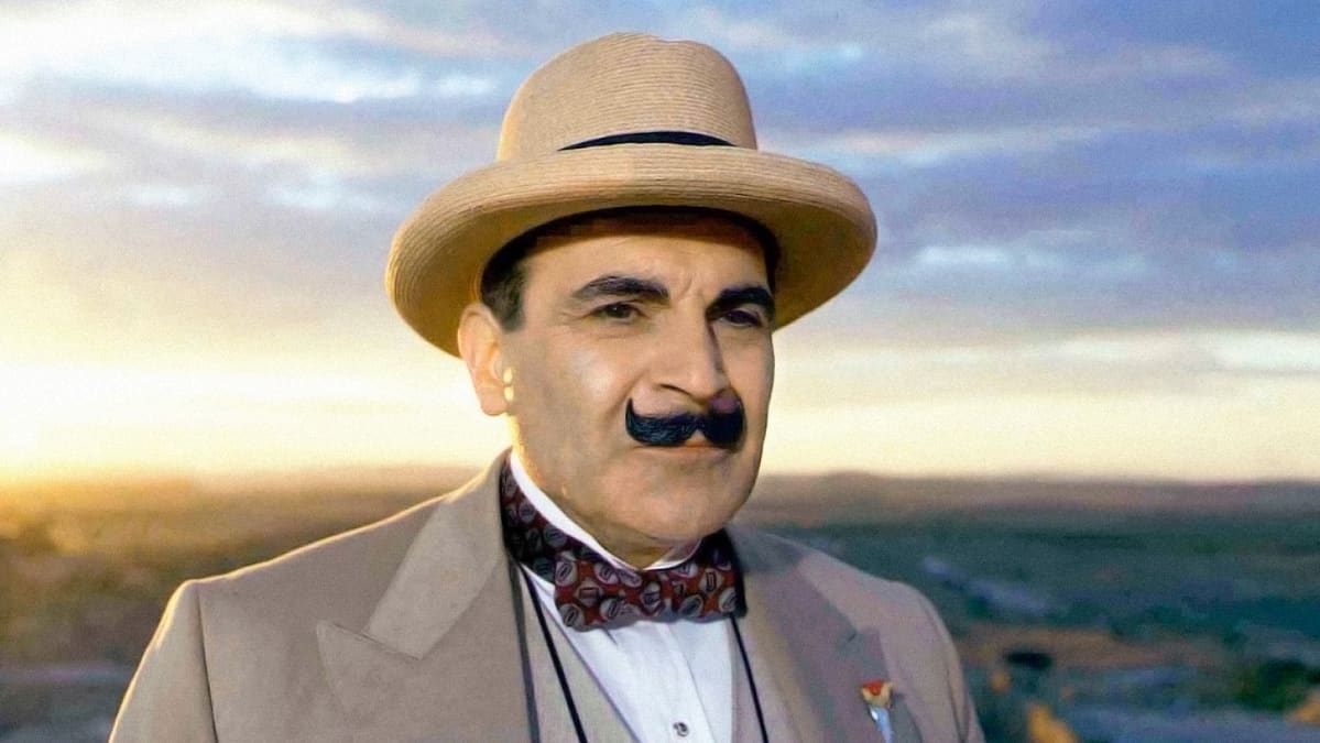 Hercule Poirot seisoo ilta-auringossa mietteliäänä olkihattu päässään.