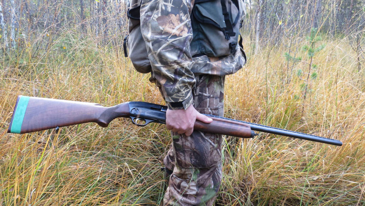 Metsästäjä ase kädessä.