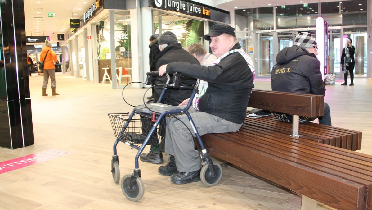 Vanhus rollaatorin kanssa kauppakeskuksessa