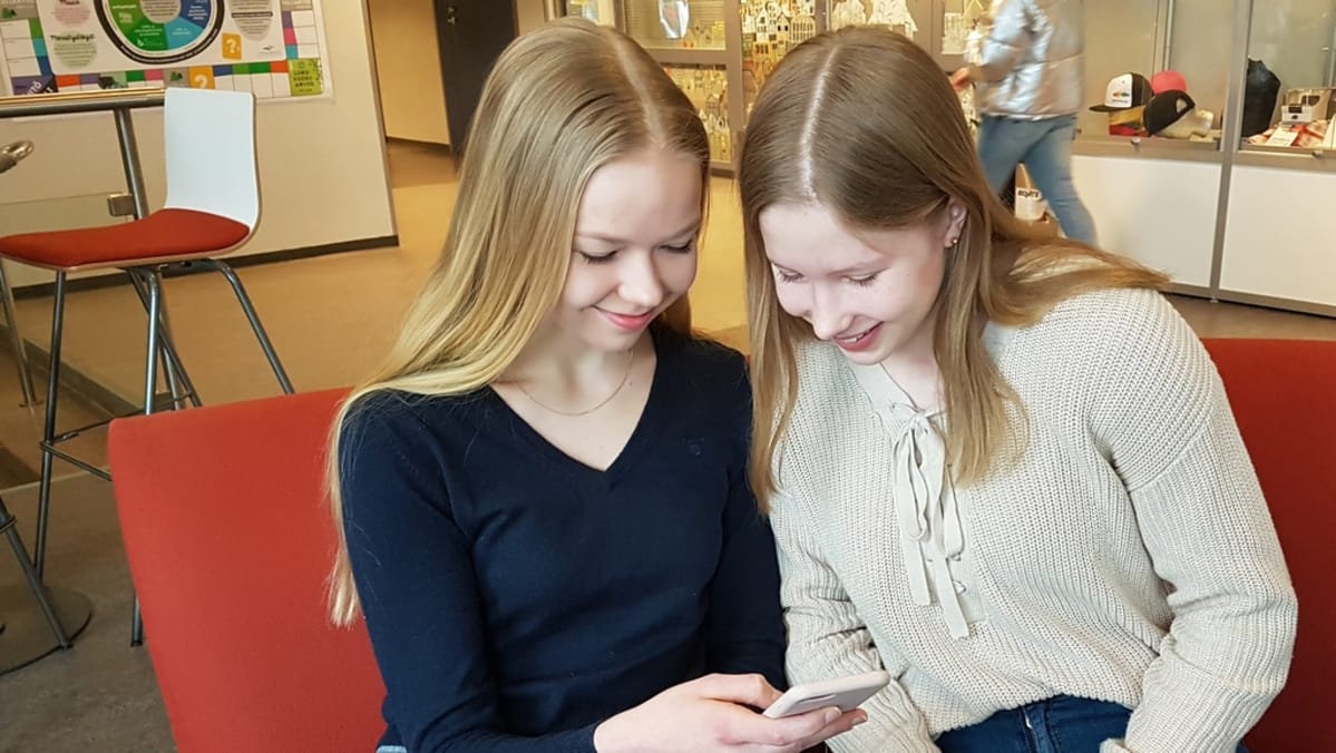 kaksi nuorta yhdeksäsluokkalaista kännyköidensä kimpussa