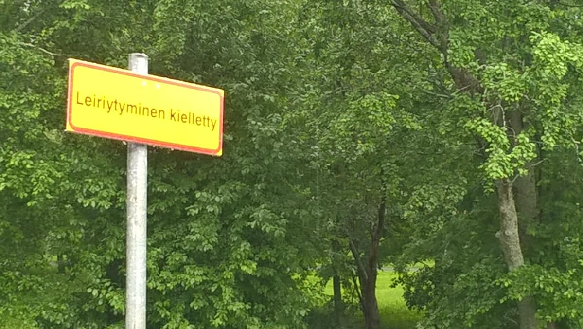 Leiriytyminen kielletty -kyltti puistoalueen reunassa.