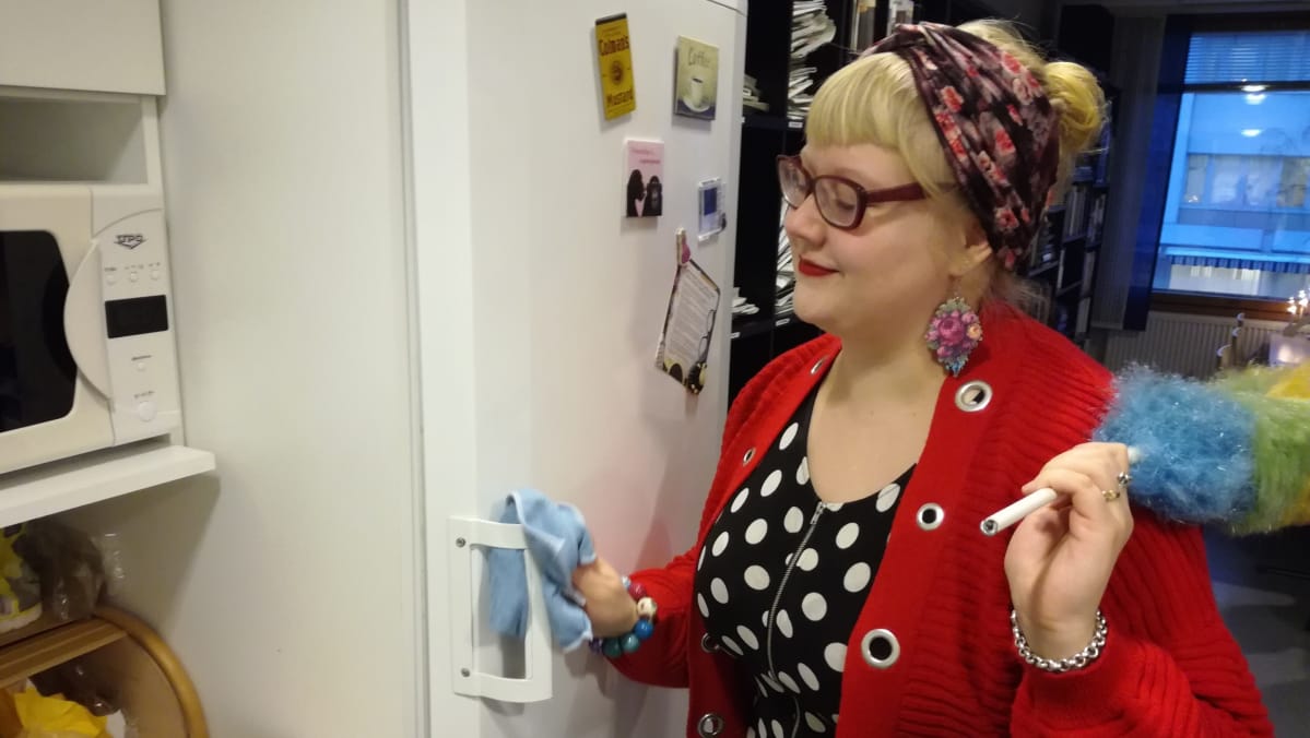 Nainen pyyhkii jääkaapin oven kahvaa