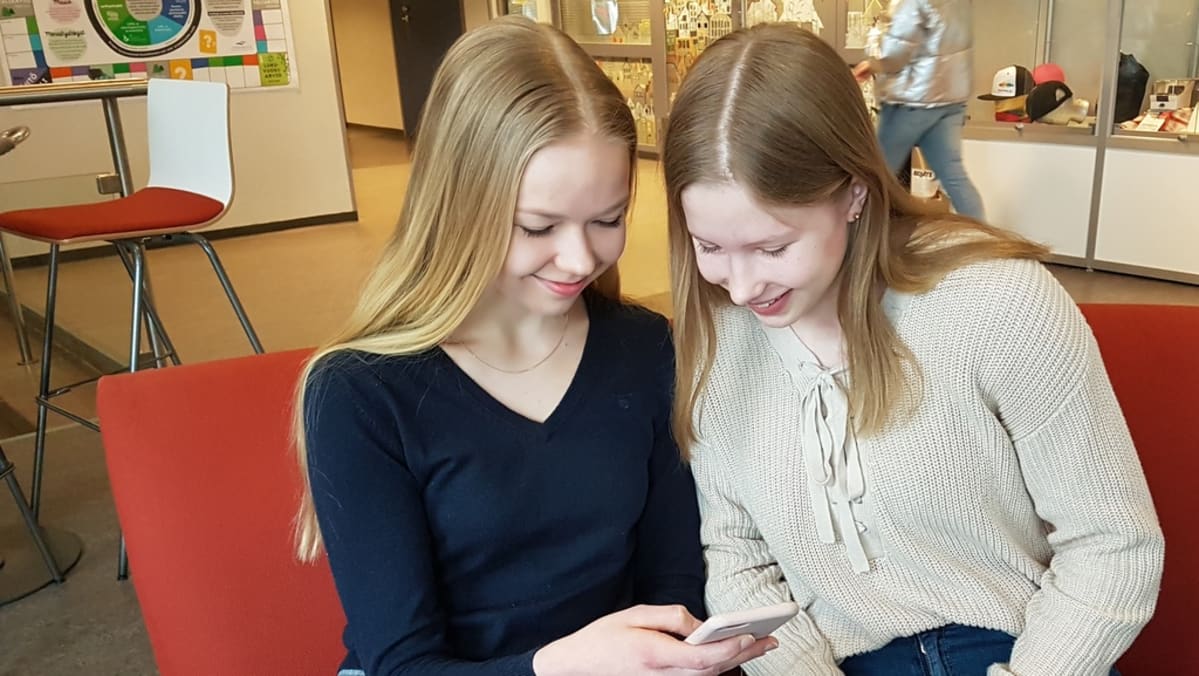 kaksi nuorta yhdeksäsluokkalaista kännyköidensä kimpussa