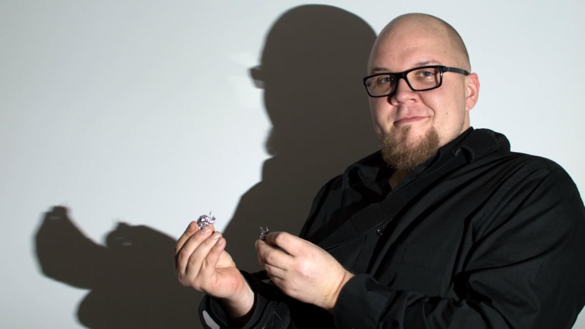 Jukka Holmstedt pitelee kädessään uuden vuoden tinaa. Taustalla tinan ja Holmstedtin varjo.