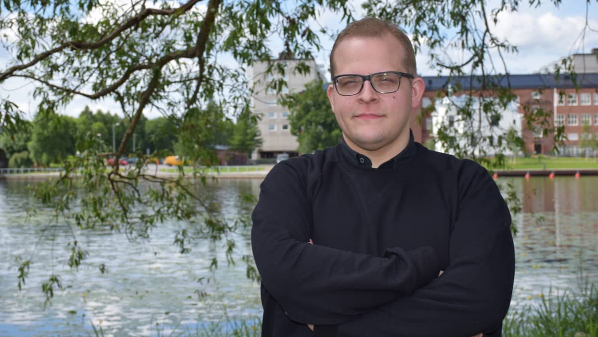Mies katsoo kameraan järven rannalla