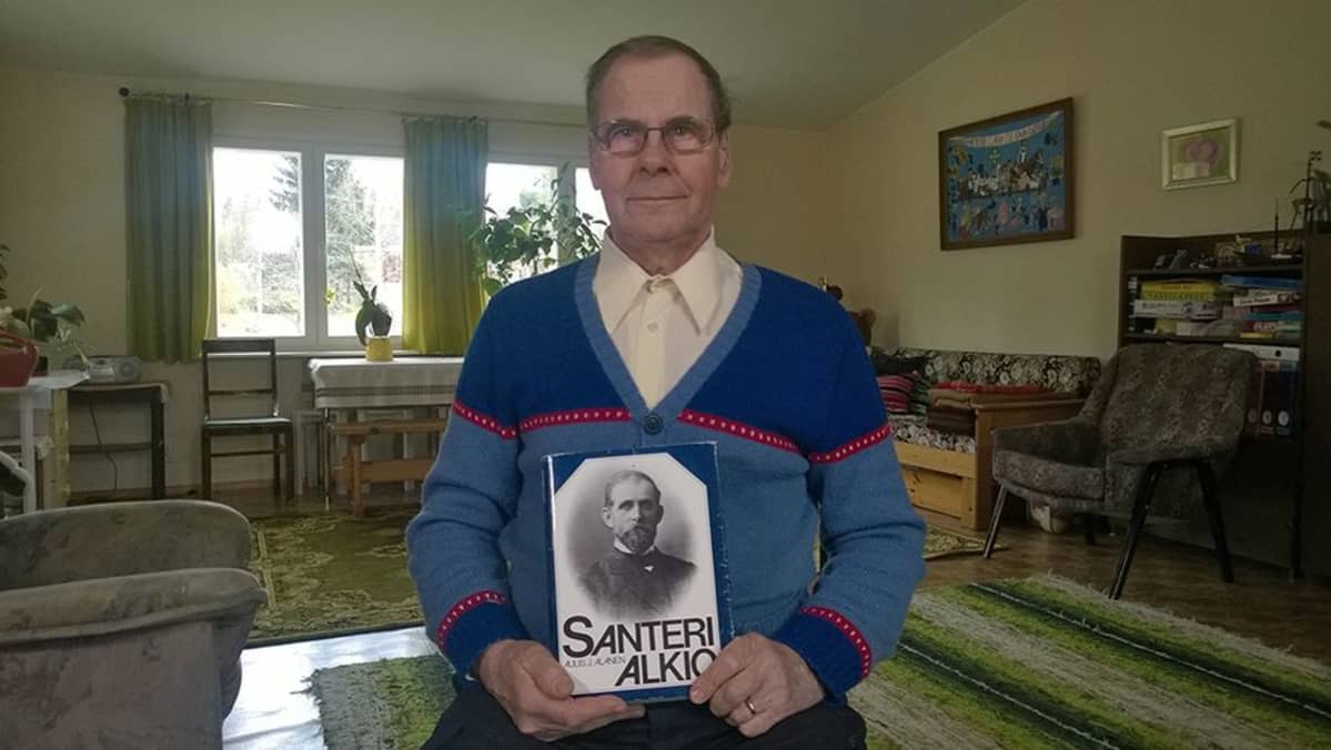 Vanhempi mies pitää Santeri Alkion kirjaa kädessään.