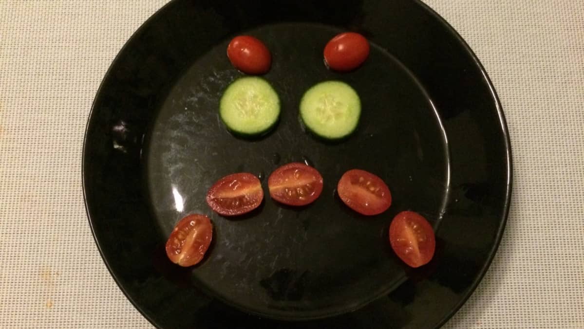 Kurkkuviipaleista ja tomaateista tehty vihainen naama lautasella.