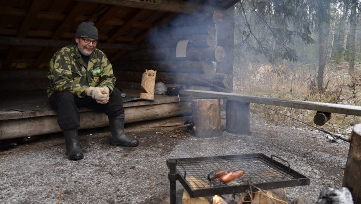 Matti Koski paistaa makkaraa nuotiolla.