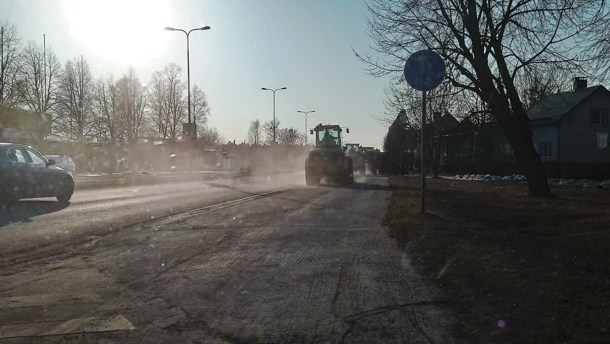 Työkone lakaisee katua pölypilvi perässään