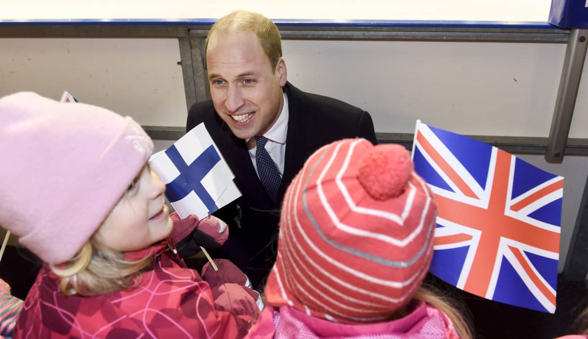 Prinssi William juttelee lapsille jotka pitävä suomen ja Englannin lippua