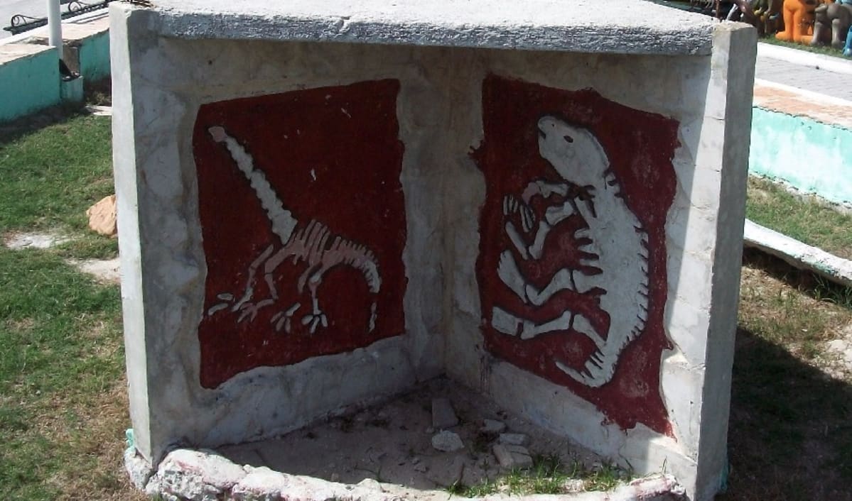 Betoninen muistomerkki, johon on maalattu kahden dinosauruksen luurangot.