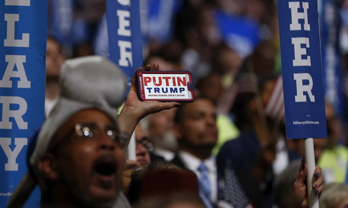 Kuva ihmismassasta Philadelphian puoluekokouksessa. Väkijoukon keskellä joku pitää esillä kännykkää, jonka näytöllä lukee: "Putin. Trump. Making Russia Great Again."