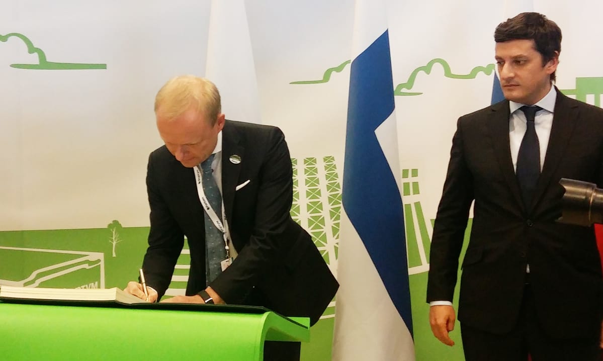 Fortumin pääjohtaja Pekka Lundmark kirjoittaa nimensä juhlakirjaan varaministeri Anton Inytsinin valvoessa.