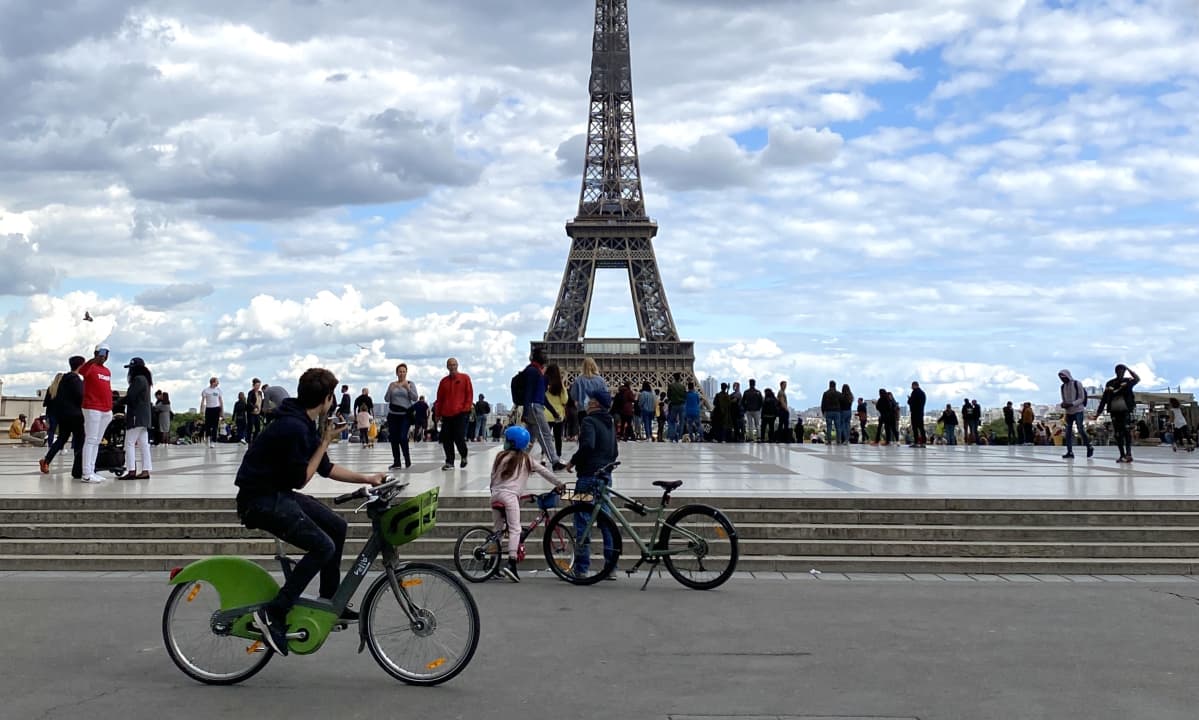 Ihmisiä pyöräilemässä Eiffel-tornin edessä