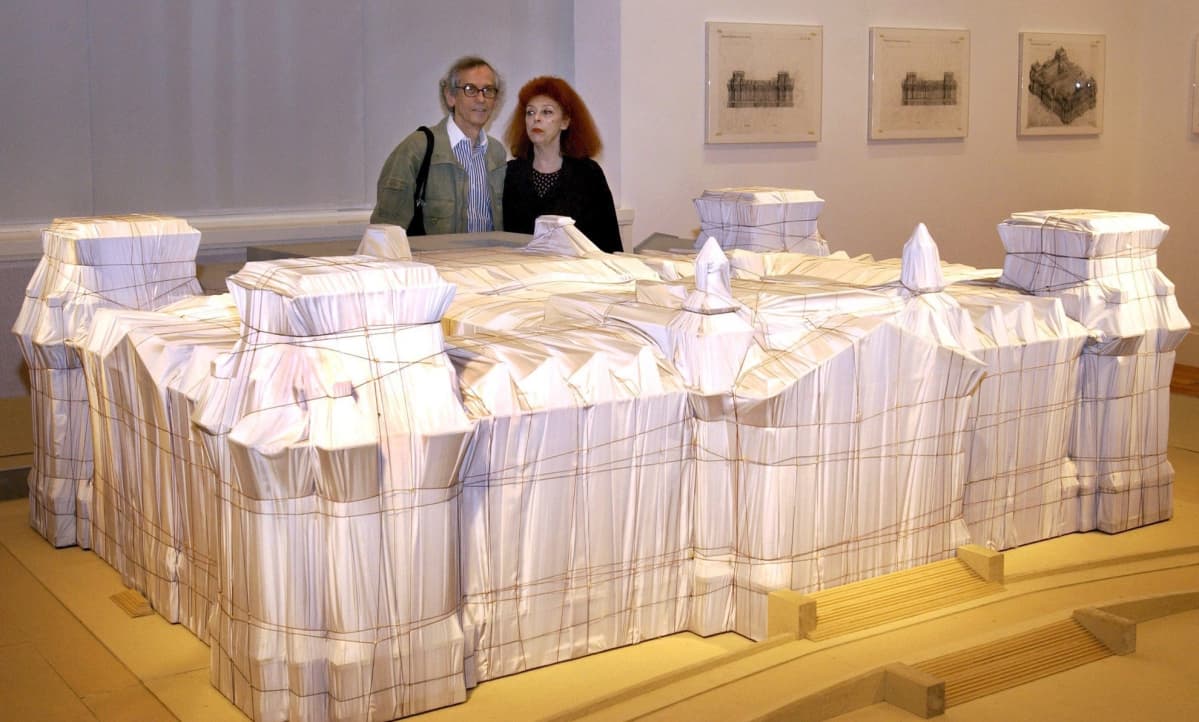 Pakkaustaiteilija Christo verhosi vuonna 1995 Berliinin Reichstagin eli Valtiopäivätalon kankaaseen. Vuonna 2001 otetussa kuvassa taiteilijapari Christo ja Jeanne-Claude poseerasivat teoksen pienoismallin takana.