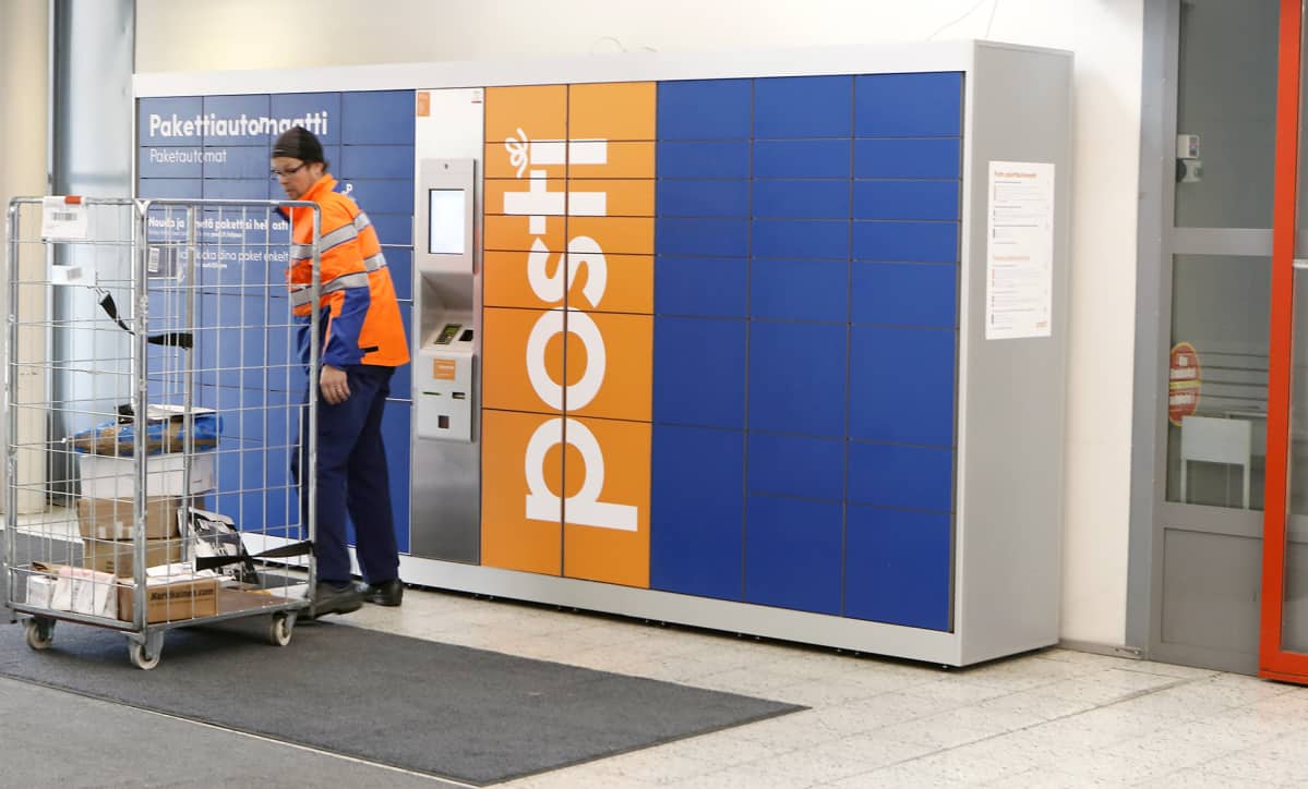 Postin työntekijä lastaa pakettiautomaattia.