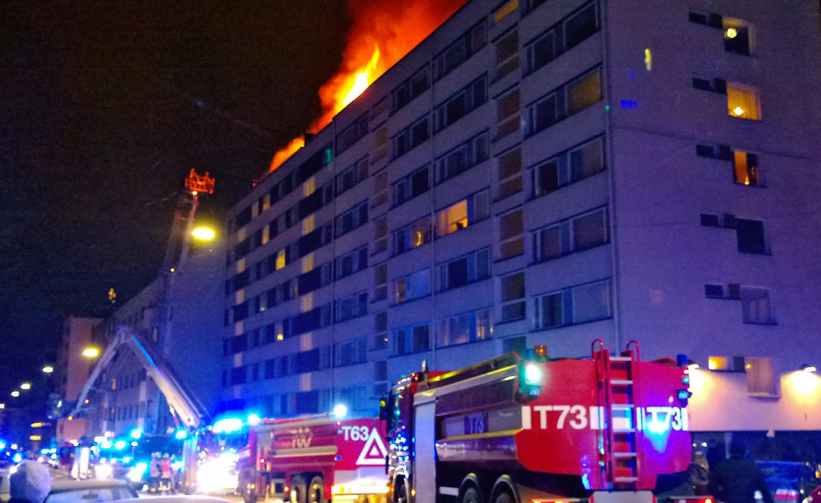 Kahdeksankerroksisen kerrostalon katolta näkyy tulenlieskoja.