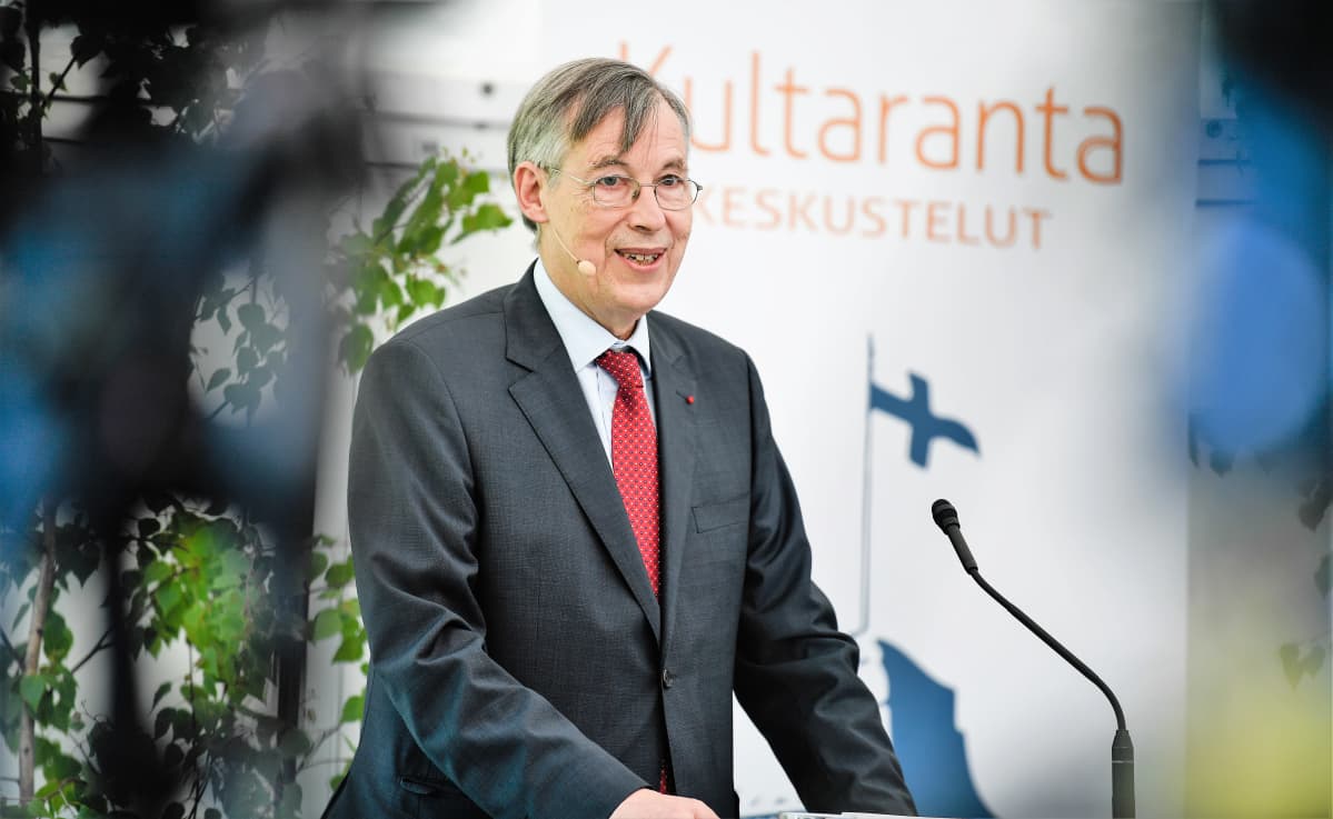 Franҫois Heisbourg puhuu mikrofoniin. Hänellä on yllään tummanharmaa puku, punainen kravatti. Taustakankaassa näkyy teksti Kultaranta-keskustelut ja Suomen lippu.