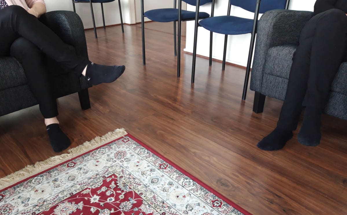Kaksi ihmistä istuu tuoleissa, vain jalat näkyvät.