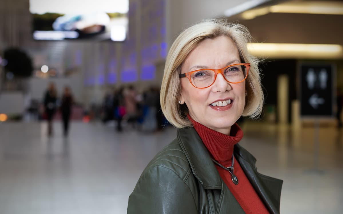Saara Hassinen, terveysteknologian ry.:n toimitusjohtaja seisoo Helsingin messukeskuksen aulassa ja hymyilee..