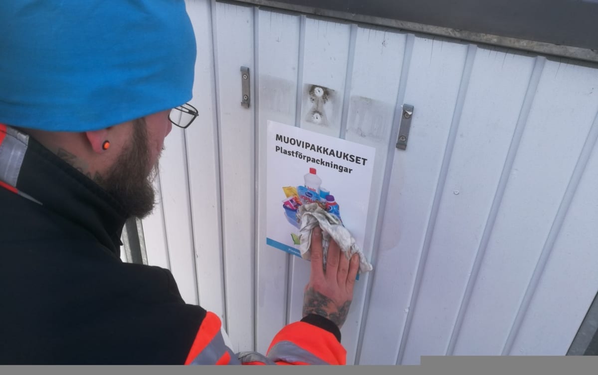 Mies teippaa muovinkeräysastiaa.