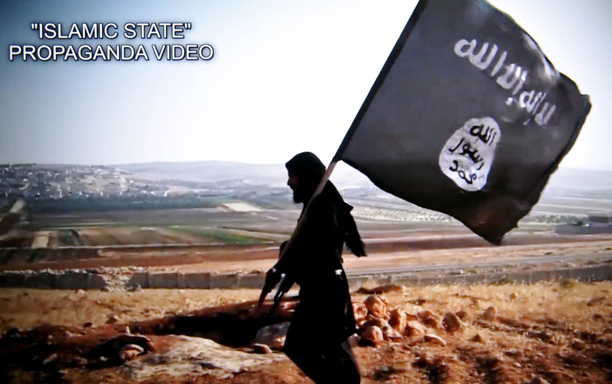 Isis-taistelija ja Isisin lippu. Kuvakaappaus Isisin videosta.