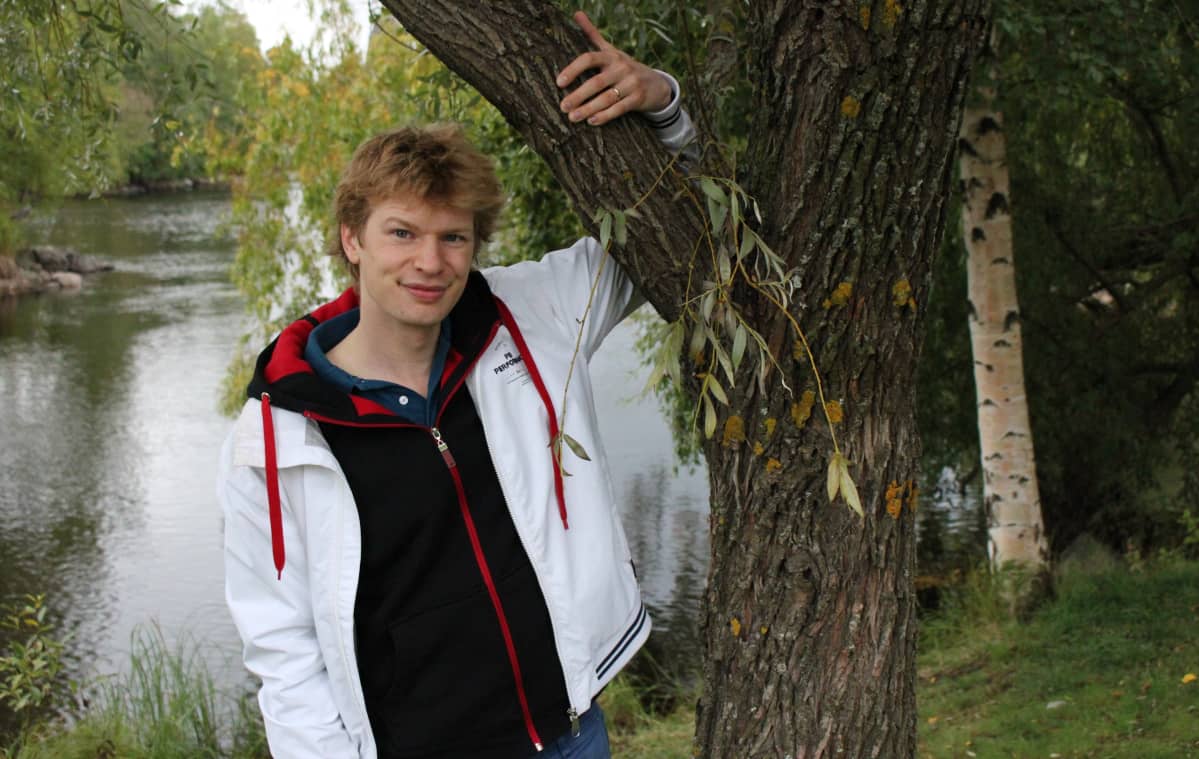 Kapellimestari Eero Lehtimäki nojaa puuhun Joensuussa Pielisjoen varrella.