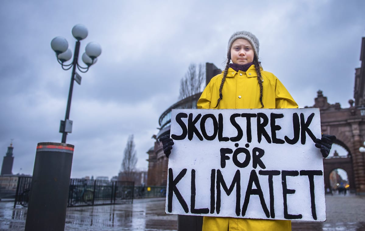 15-vuotias ruotsalainen Greta Thunberg pitelee kylttiä, jossa lukee "koululakko ilmaston puolesta". Hän istuu Ruotsin parlamenttitalon edessä perjantaisin, kunnes maa noudattaa Pariisin sopimuksen mukaista ilmastopolitiikkaa.