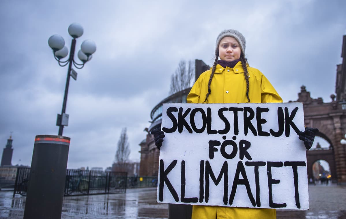 15-vuotias ruotsalainen Greta Thunberg pitelee kylttiä, jossa lukee "koululakko ilmaston puolesta". Hän istuu Ruotsin parlamenttitalon edessä perjantaisin, kunnes maa noudattaa Pariisin sopimuksen mukaista ilmastopolitiikkaa.