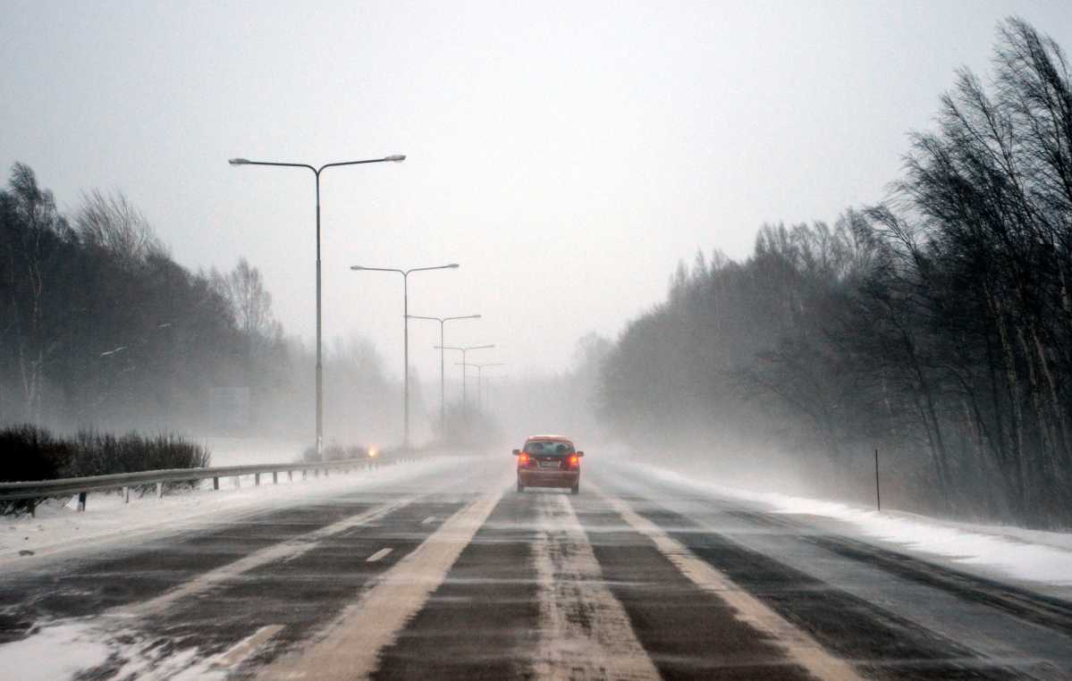 Auto moottoritiellä, lumisade, lymipyry, pöllyävä lumi