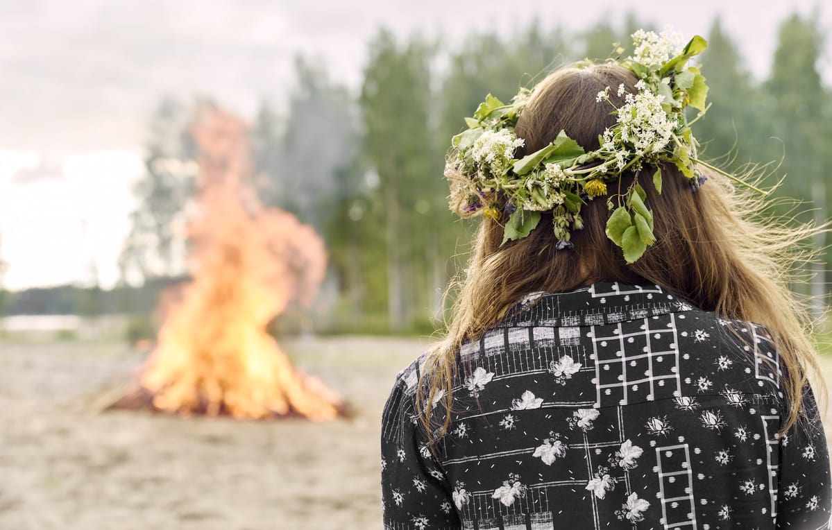 Nuori nainen katsoo juhannuskokkoa.