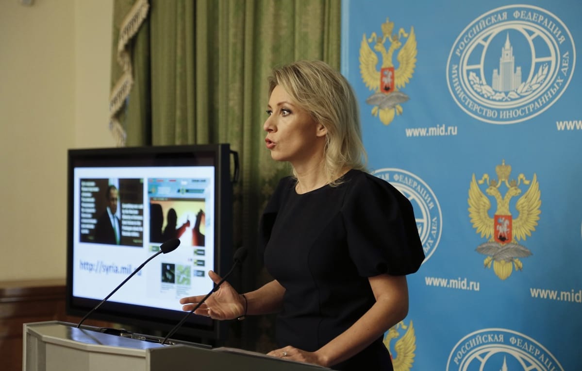 Musta-asuinen Zaharova puhuu puhujanpöntön takana. Taustalla näkyy Venäjän ulkoministeriön logoilla ja Venäjän vaakunakuvilla varusteltu sininen kangas ja vihreää verhoa.
