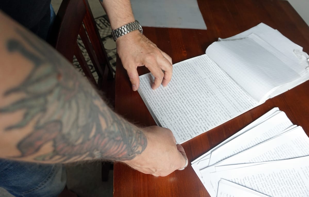 Tatuoitu käsi selaa lehtiötä