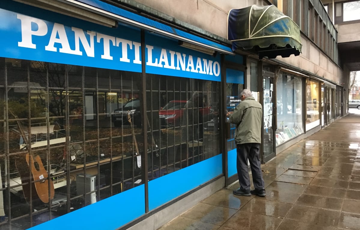Kymen Panttilainaamon ulkosivu. Yrittäjä Seppo Heikkilä lukitsee ovea.
