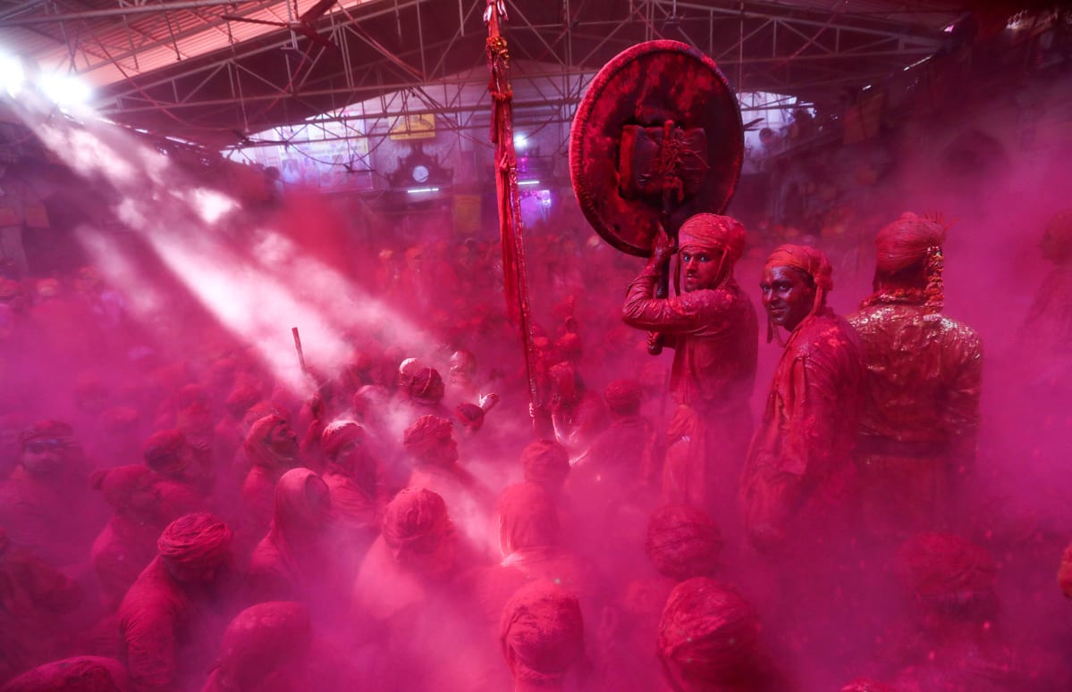 Hindumiehet magentan värisen jauheen peitossa juhlivat festivaalilla.