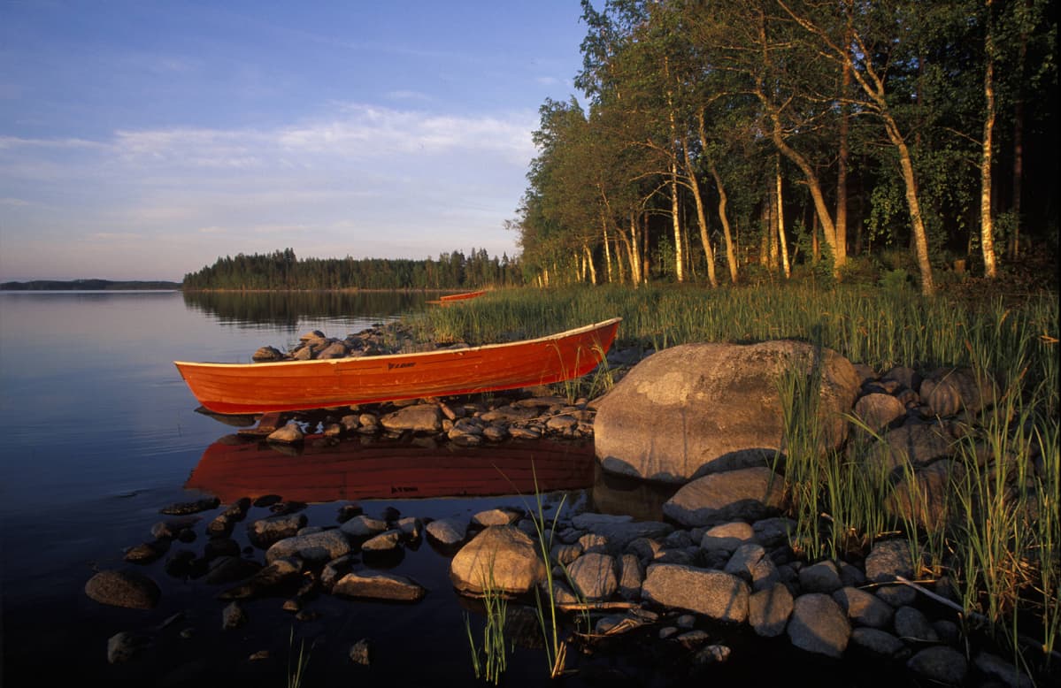 Saimaan rannalla soutuvene auringon laskiessa.