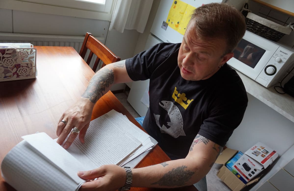 Marko Pesonen istuu pöydän ääressä selaamassa lehtiötä
