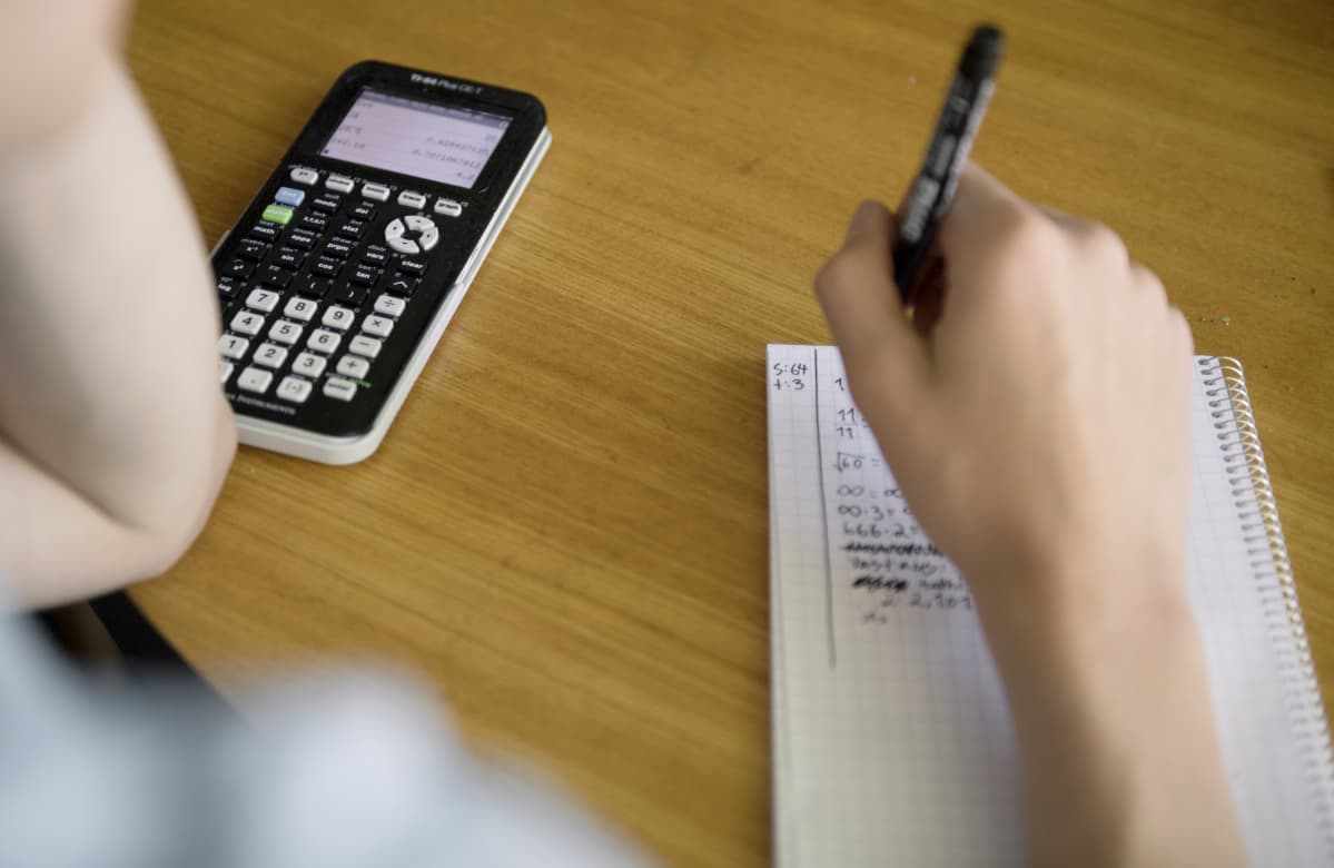 Nuori laskee matematiikan tehtäviä.
