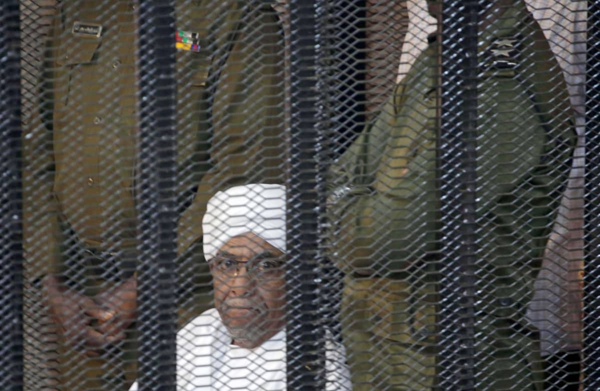 Sudanin entinen presidentti Omar al-Bashir seuraa oikeudenkäyntiään vankikopista Khartumissa.