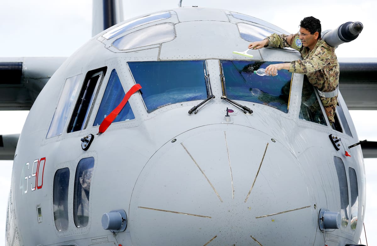 Italian huoltojoukkojen upseeri pesee Italian ilmavoimien C-27J Spartan -koneen tuulilasia.