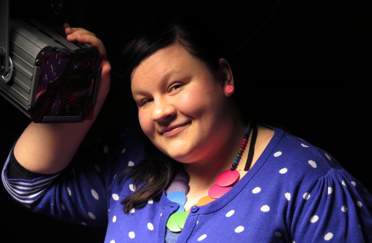 Maija Nousianen pitää kättään teatterilampun päällä ja katsoo kameraan