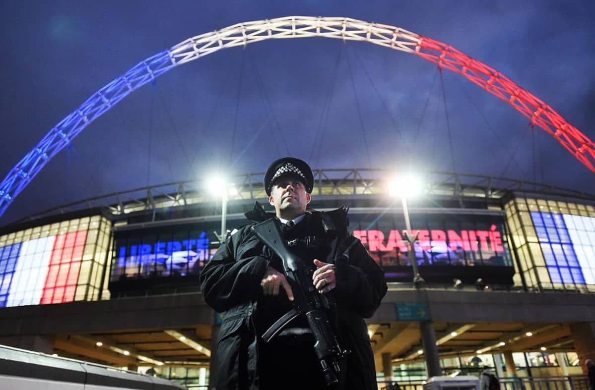 Aseistautunut poliisi seisoo Ranskan lipun värein valaistun Wembleyn stadionin kaaren edustalla.